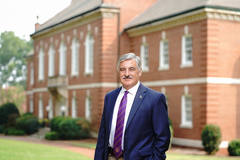 Dr. Stewart standing in front of brick building