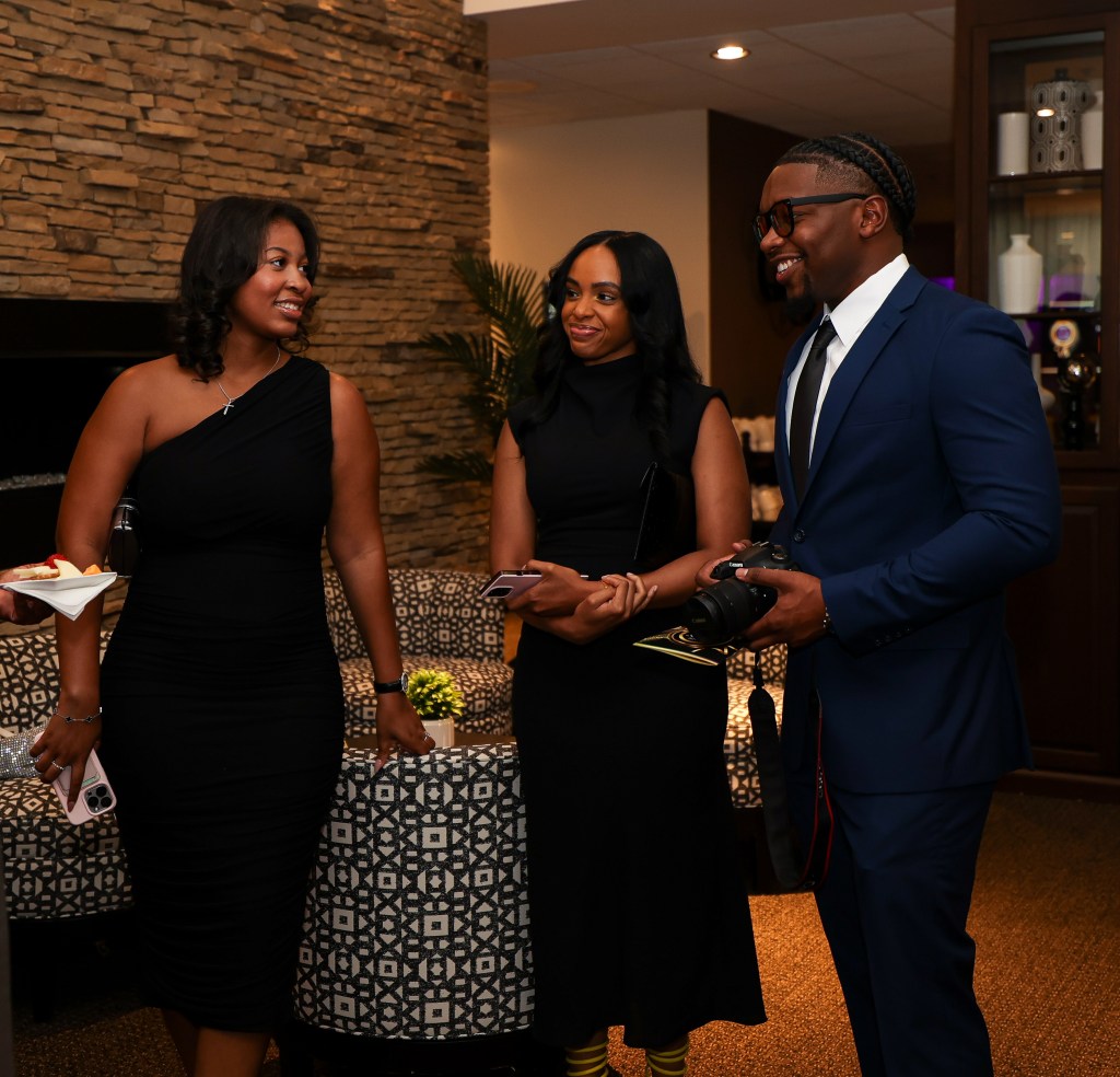 Three well-dressed people standing around conversing.