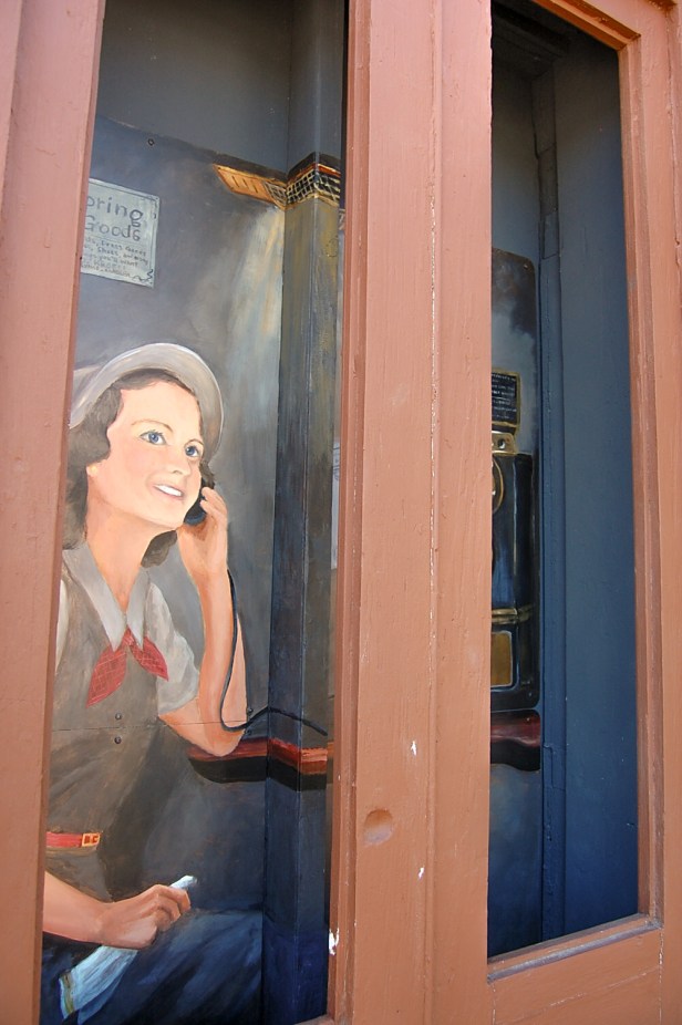 painted lady taking a call in a phone booth